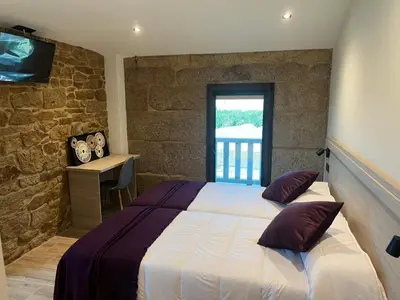 a bedroom with a bed and a desk and a television at A Casa do Pillado in Vilariño