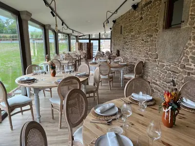 a restaurant with tables and chairs and a stone wall at A Casa do Pillado in Vilariño