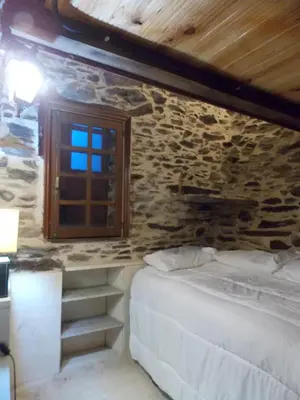 a bedroom with a bed and a stone wall at Granja del Peregrino in O Pino