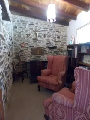 a living room with two chairs and a stone wall at Granja del Peregrino in O Pino