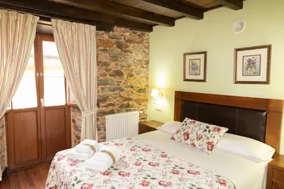 a bedroom with a bed and a stone wall at Apartamentos Turisticos A Estacion in A Pontenova