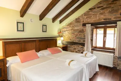 a bedroom with two beds with white sheets and orange pillows at Apartamentos Turisticos A Estacion in A Pontenova