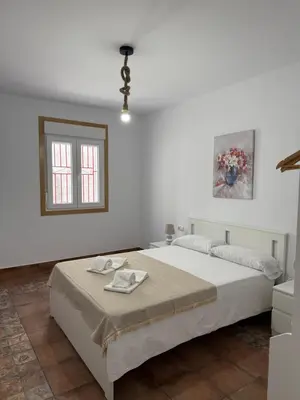 a white bedroom with a bed and a window at Primavera in Padrón