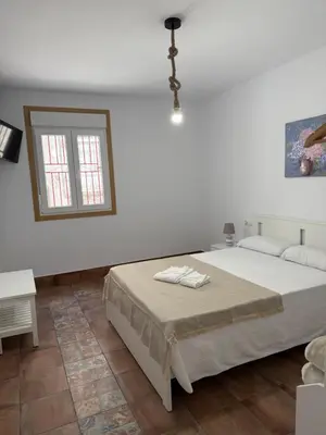 a white bedroom with a bed and a window at Primavera in Padrón