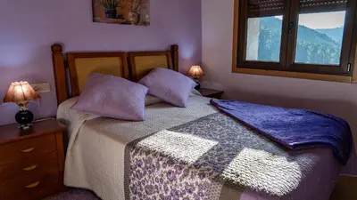 a bedroom with a bed with purple pillows and a window at Casa El Mirador del Miño en la Ribeira Sacra in Rosende