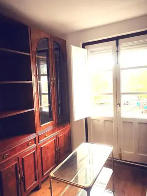 a room with a glass table and some wooden cabinets at Apartamento MIZA in Ponferrada