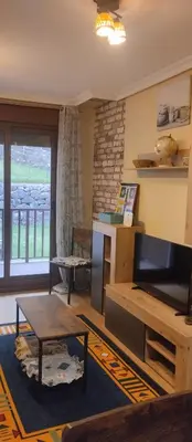 a living room with a television and a table at La Vega De Somiedo in Pola de Somiedo