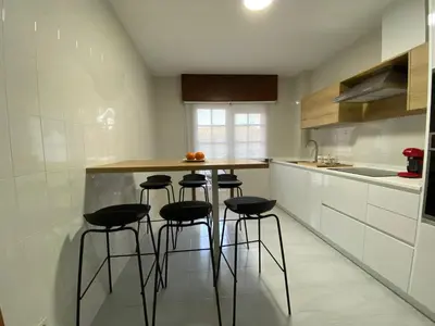 a kitchen with a counter with stools in it at A tres Pasos in Caldas de Reis