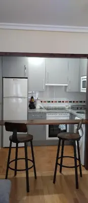 a kitchen with a wooden table and two chairs at La Vega De Somiedo 1 in Aguino