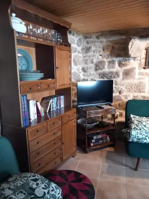a living room with a tv and a stone wall at A casa da Touza in Pensos