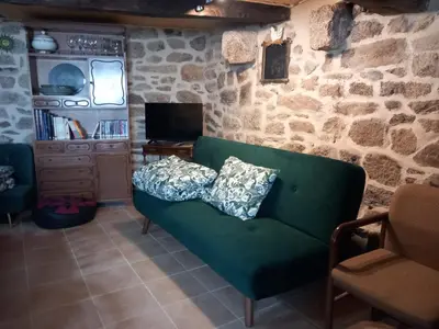 a living room with a green couch and a stone wall at A casa da Touza in Pensos