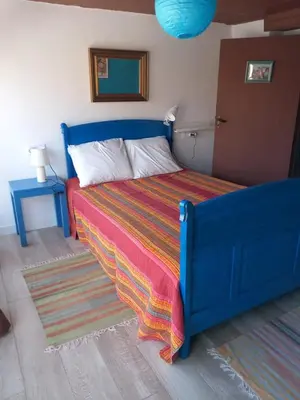 a bedroom with a blue bed with a colorful blanket at A casa da Touza in Pensos