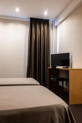 a room with two beds and a desk with a computer at AS Hoteles Ponferrada in Columbrianos