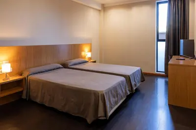 a hotel room with two beds and a television at AS Hoteles Ponferrada in Columbrianos