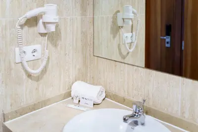 a bathroom with a sink and a mirror and a phone at AS Hoteles Ponferrada in Columbrianos