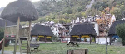 a group of buildings with thatched roofs and benches at La Vega De Somiedo 2 in Pola de Somiedo