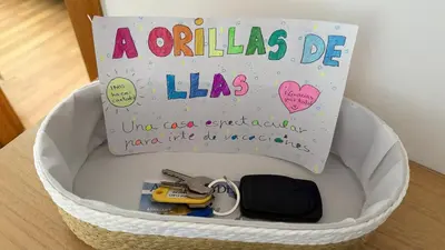 a white basket with a sign and keys in it at A Orillas de Llas in Foz