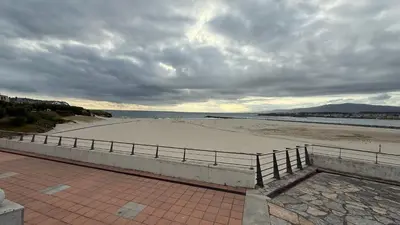a sandy beach with a fence next to the ocean at A Orillas de Llas in Foz