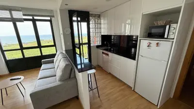 a kitchen with a refrigerator and a couch and a table at A Orillas de Llas in Foz