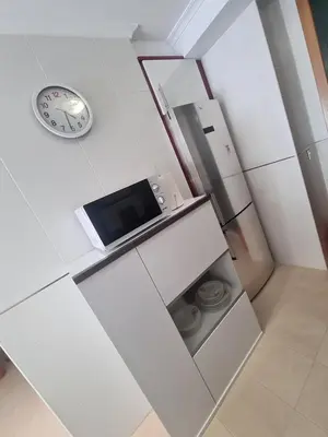 a white kitchen with a microwave and a clock at Apartment in Costa with Spa, Jacuzzi in San Miguel de Reinante