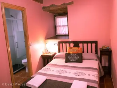 a bedroom with a bed with pink walls at Hotel Rural El Lagar De Las Médulas in Orellán