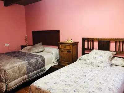 two beds in a room with pink walls at Hotel Rural El Lagar De Las Médulas in Orellán