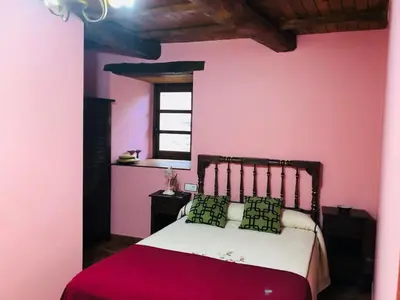 a bedroom with a bed with pink walls and a window at Hotel Rural El Lagar De Las Médulas in Orellán