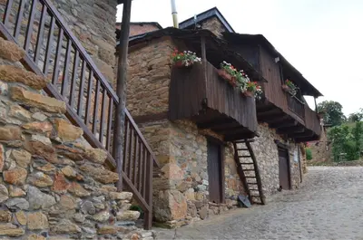 a stone building with flower boxes and a staircase at Hotel Rural El Lagar De Las Médulas in Orellán