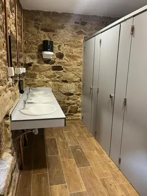 a bathroom with two sinks and a stone wall at Albergue Freixo in Palas de Rei
