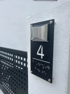 a sign on the side of a building with the number four at Albergue Freixo in Palas de Rei