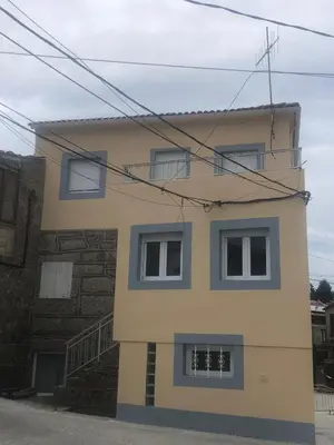 a yellow building with three windows and a staircase at A Castelana de Cea in Cea