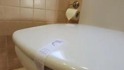 a toilet seat with a sign on it in a bathroom at Camin de Muniellos apartamentos rurales in Cangas del Narcea