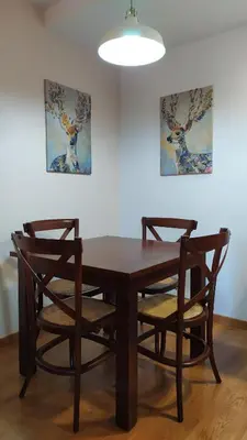 a wooden table with two chairs and a lamp at Camin de Muniellos apartamentos rurales in Cangas del Narcea