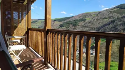 a balcony with a chair and a view of mountains at Camin de Muniellos apartamentos rurales in Cangas del Narcea