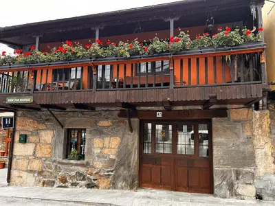 a building with a balcony with flowers on it at Hostal Casa San Nicolas in Molinaseca
