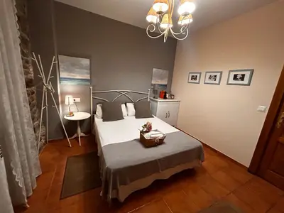 a bedroom with a bed and a table and a chandelier at Hostal Casa San Nicolas in Molinaseca