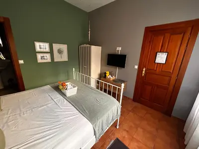 a bedroom with a bed and a refrigerator at Hostal Casa San Nicolas in Molinaseca