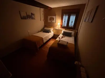 a small room with two beds and a window at Hostal Casa San Nicolas in Molinaseca