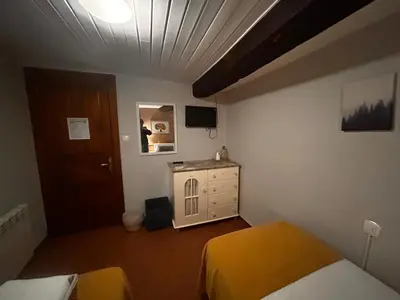 a bedroom with two beds and a dresser and a door at Hostal Casa San Nicolas in Molinaseca