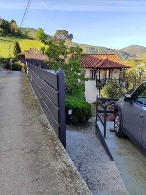a car parked next to a fence in front of a house at La Casina de Santulaya in Adralés