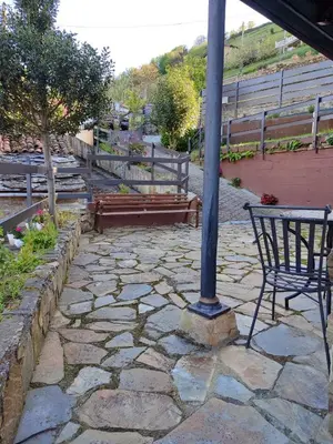 a stone patio with a bench and a pole at La Casina de Santulaya in Adralés