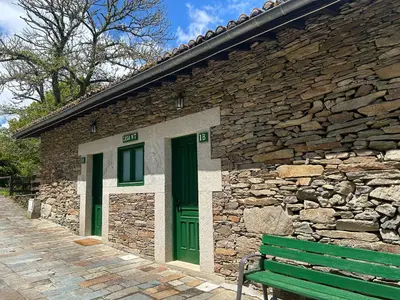a stone building with green doors and a green bench at Couso Relax in Sarreaus