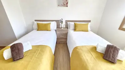 two twin beds in a room with yellow cushions at Apartamentos Pedras do Val in Mondariz
