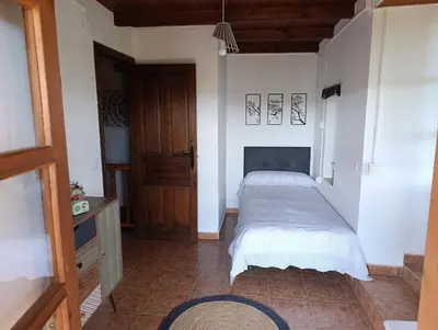 a bedroom with two beds and a wooden door at Finca el Filandón in San Miguel de Arganza