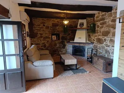 a living room with a stone fireplace and a chair at Finca el Filandón in San Miguel de Arganza