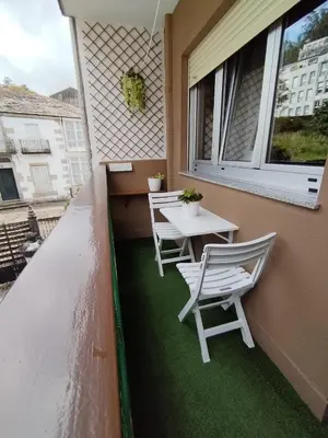 a balcony with two chairs and a table and a window at Lannion in Viveiro