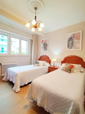 a bedroom with two beds and a chandelier at Lannion in Viveiro