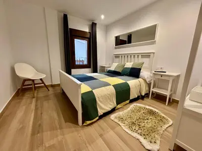 a bedroom with a bed and a table and a chair at Apartamentos O Grilo in Doade