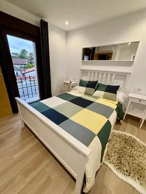 a bedroom with a large bed with a large window at Apartamentos O Grilo in Doade
