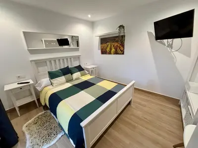 a bedroom with a bed and a flat screen tv at Apartamentos O Grilo in Doade